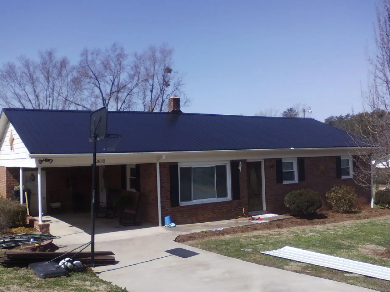 Finished dark blue metal roof on a brick ranch with a carport in Bevington