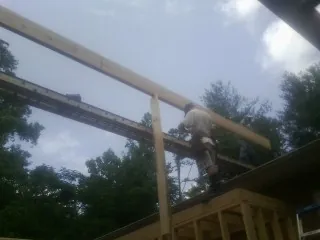 Carpenter setting a ridge beam over a new addition frame — Ice Dam Removal by Roofing Brothers in Bevington
