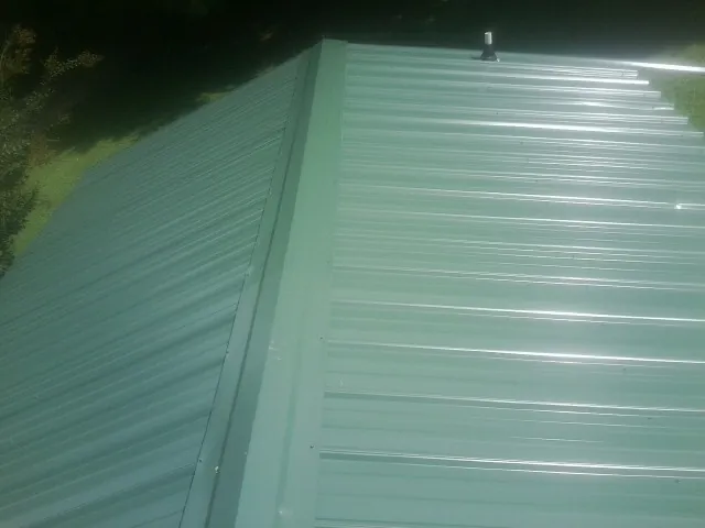 New green metal panels meeting at the ridge of a roof — Flat Roof Repair work by our crew in Bevington