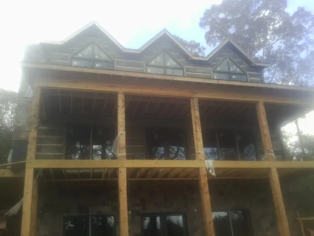 Dormers and porch framing on a large log home under construction — Roof Coating work by our crew in Bevington