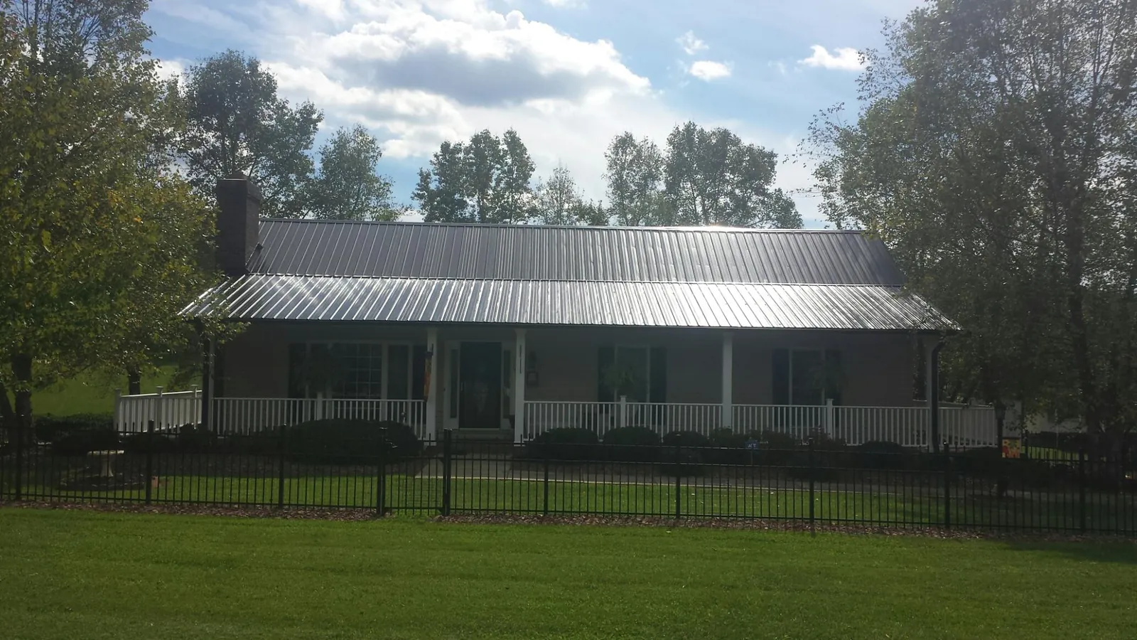 Gray metal roof on a brick ranch with a full width front porch — Gutter Guard Installation work by our crew in Bevington