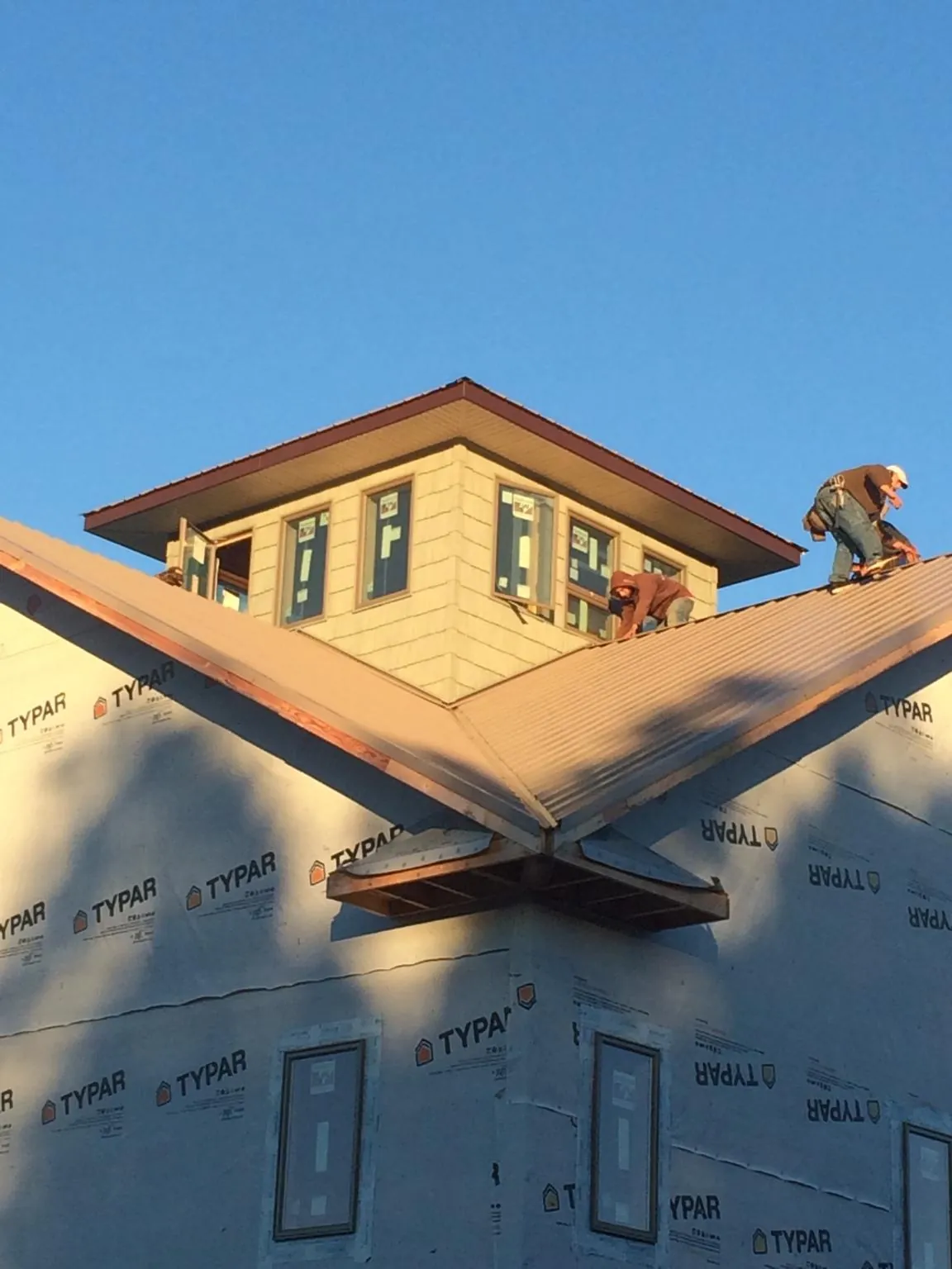 Roofers working around a rooftop cupola on a new metal roof at sunset — Roof Waterproofing in Bevington by Roofing Brothers